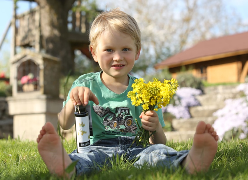 Leo-mit-Öl_Kategorie Kind sitzt auf der Wiese mit Öl der Farmgoodies